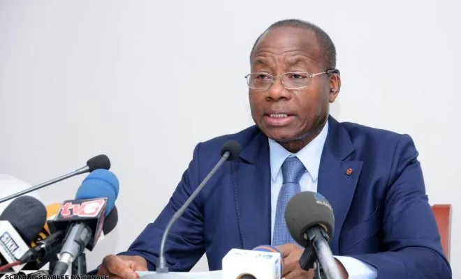 Homme en costume bleu parlant devant plusieurs micros lors d une conférence de presse