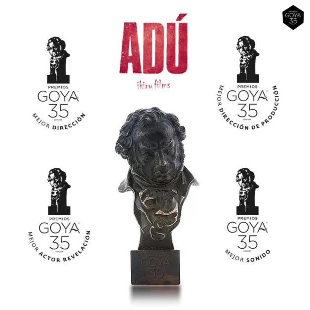Quatre trophées Goya entourent un buste noir avec le titre rouge Adú sur fond blanc