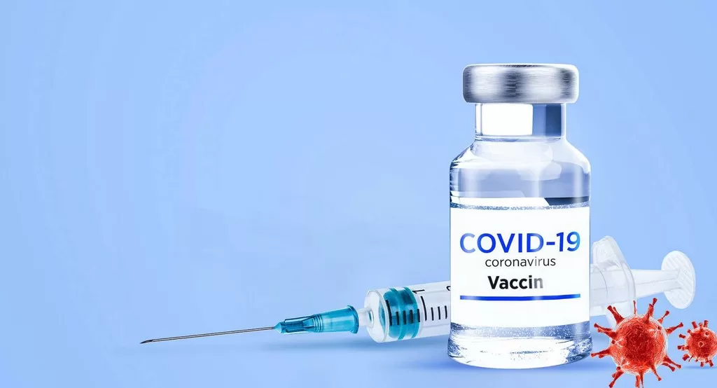 Un flacon de vaccin posé devant une seringue avec des représentations graphiques du virus sur fond bleu