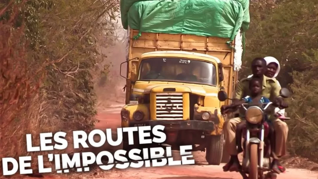 Camion chargé et plusieurs personnes à moto sur une piste poussiéreuse bordée d arbres secs avec un texte en blanc au premier plan