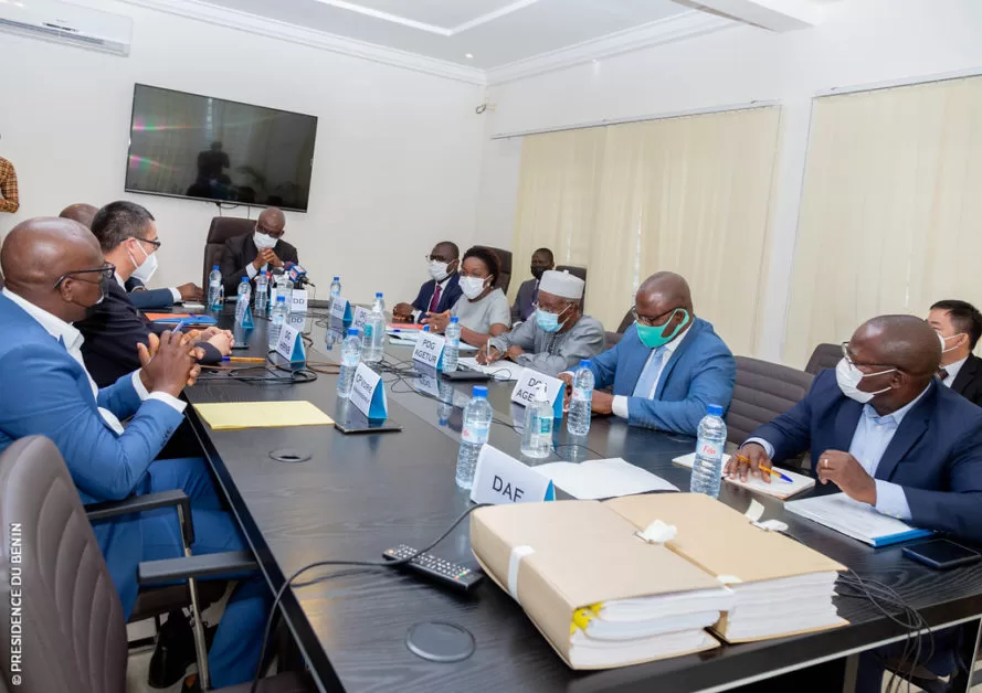 Personnes assises autour d’une table de réunion dans une salle équipée d’un écran plat au mur