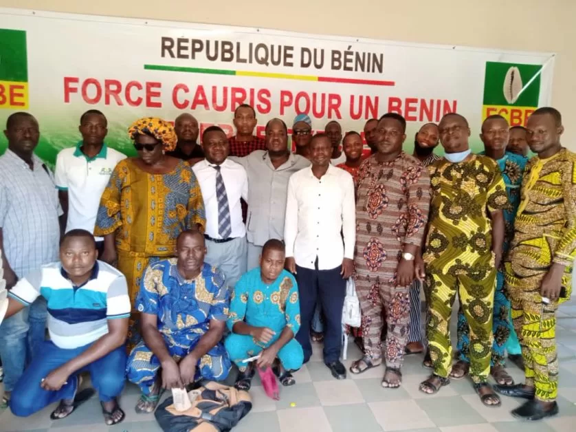 Groupe d'hommes posant devant une banderole avec inscriptions en français sur un mur intérieur