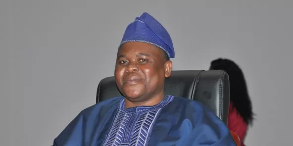 Homme souriant habillé en tenue traditionnelle bleue et coiffé d'un bonnet assorti assis sur une chaise noire
