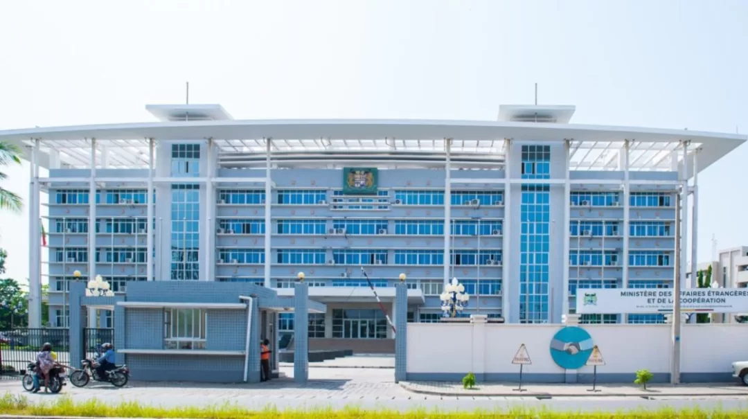 Bâtiment administratif moderne à plusieurs étages avec accès sécurisé et panneaux d'information visibles à l'entrée