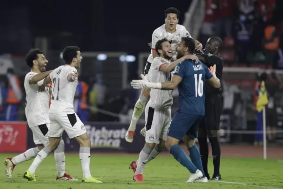 Des joueurs de football en maillots clairs célèbrent un but sur le terrain avec enthousiasme et joie partagée