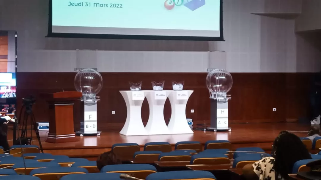 Salle avec rangées de sièges vides et présentation avec urnes transparentes et pupitre sur scène