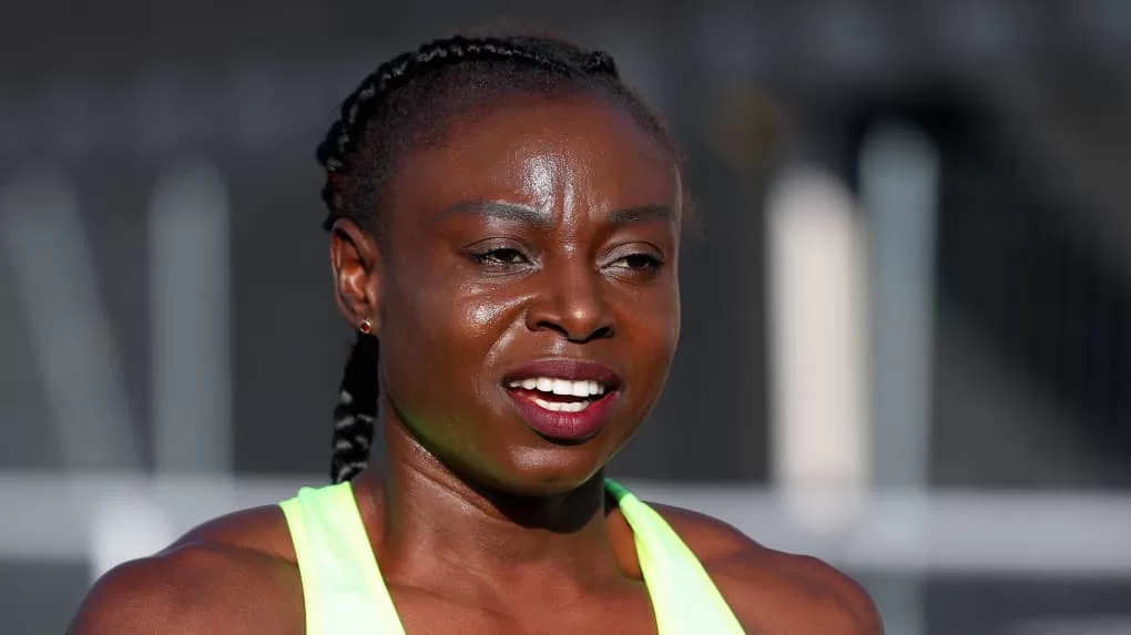 Athlète féminine en tenue de sport fluorescent sous la lumière du jour avec arrière-plan flou.