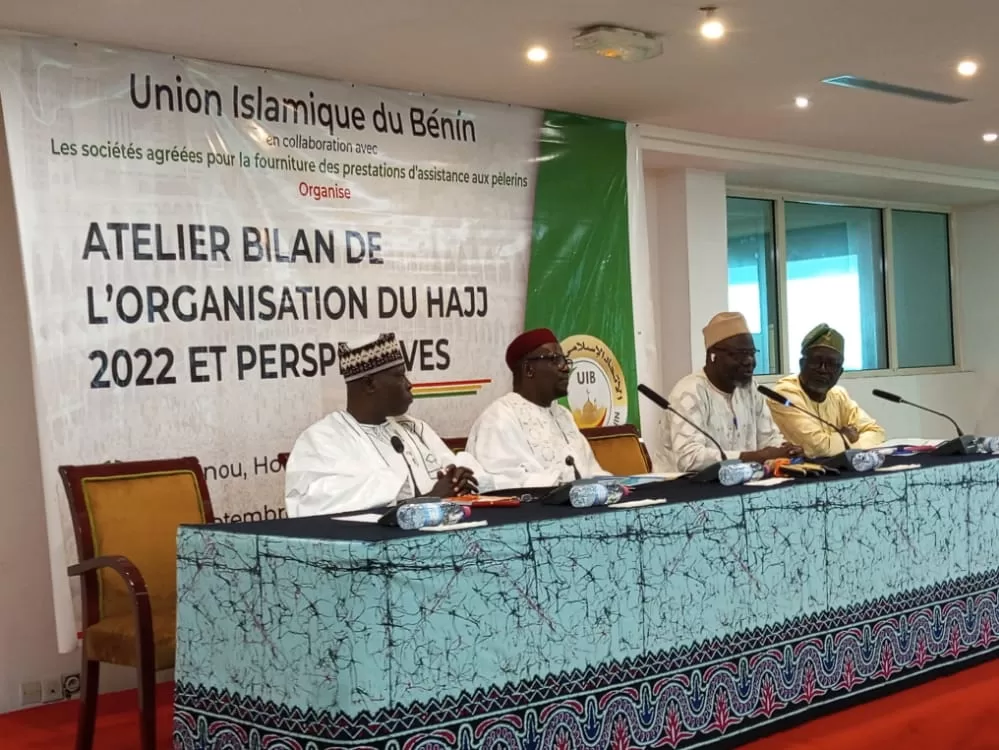 Quatre hommes en tenue traditionnelle assis derrière une table lors d un atelier avec une bannière sur l organisation du Hajj 2022