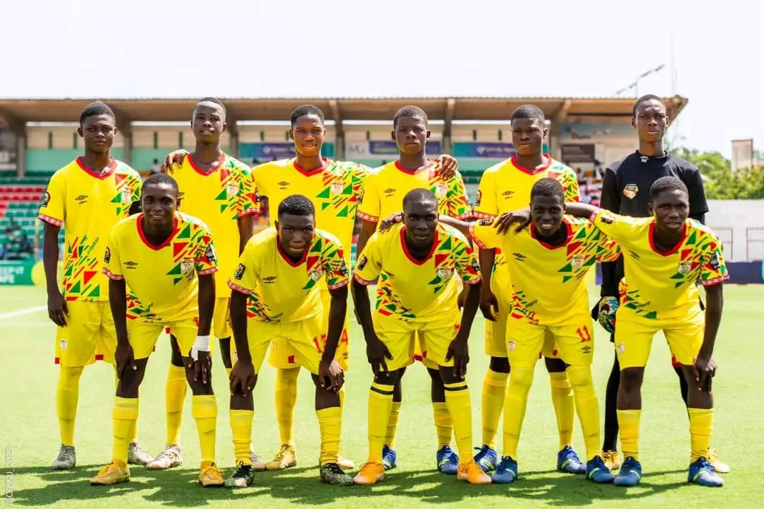 Onze jeunes joueurs de football en tenue jaune posant sur un terrain avant un match sous un ciel clair