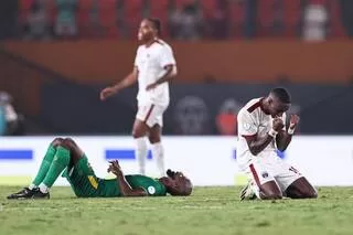 Deux joueurs de football au sol et à genoux exprimant des émotions fortes pendant un match sur un terrain vert