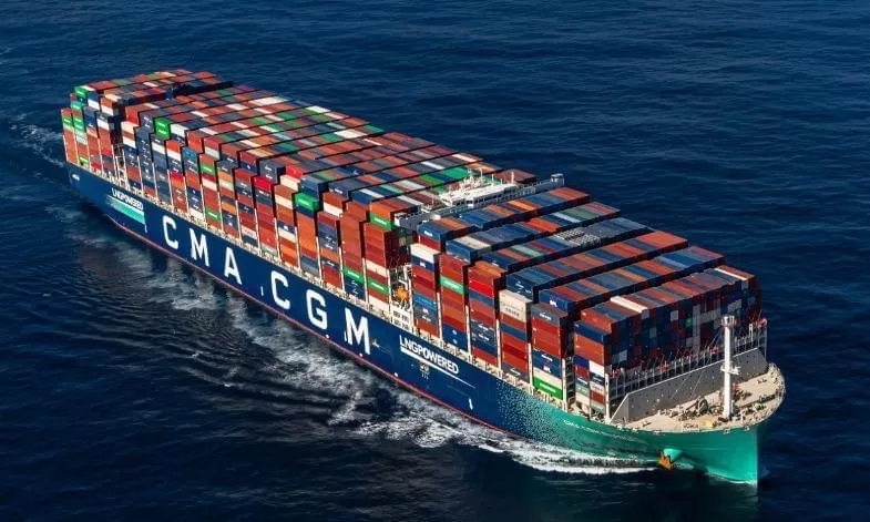 Grand porte-conteneurs bleu chargé de nombreux conteneurs multicolores naviguant en pleine mer