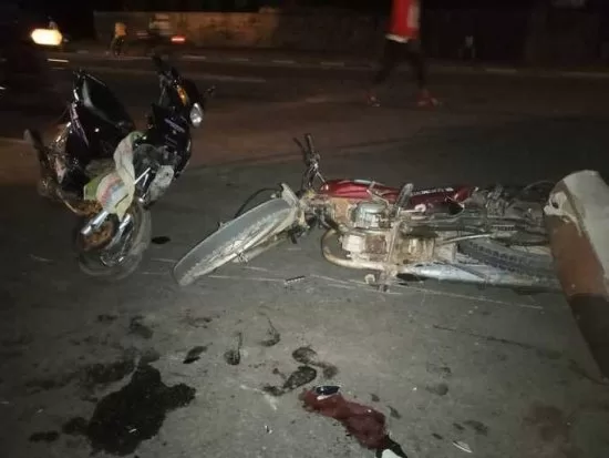 Deux motos renversées au sol la nuit avec des traces de liquide et un gant rouge près des véhicules