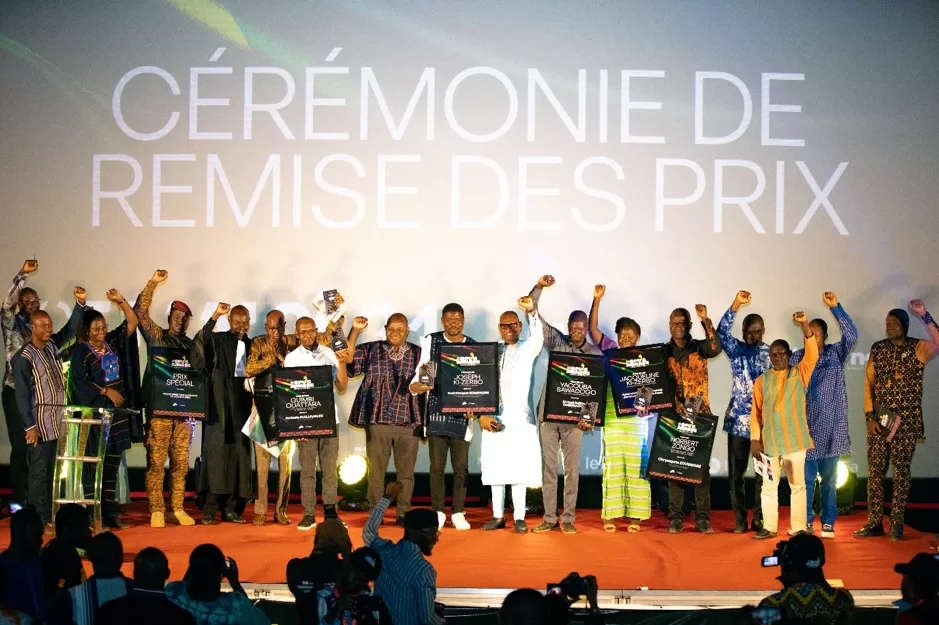 Plusieurs personnes debout sur scène brandissent des trophées lors d'une cérémonie de remise des prix