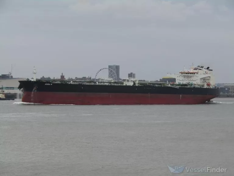 Pétrolier noir et rouge naviguant sur un large cours d’eau avec une grande roue et des immeubles en arrière-plan