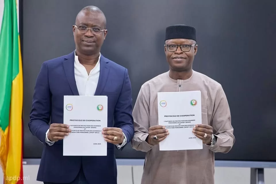 Deux hommes tenant un document officiel avec les drapeaux du Bénin en arrière-plan