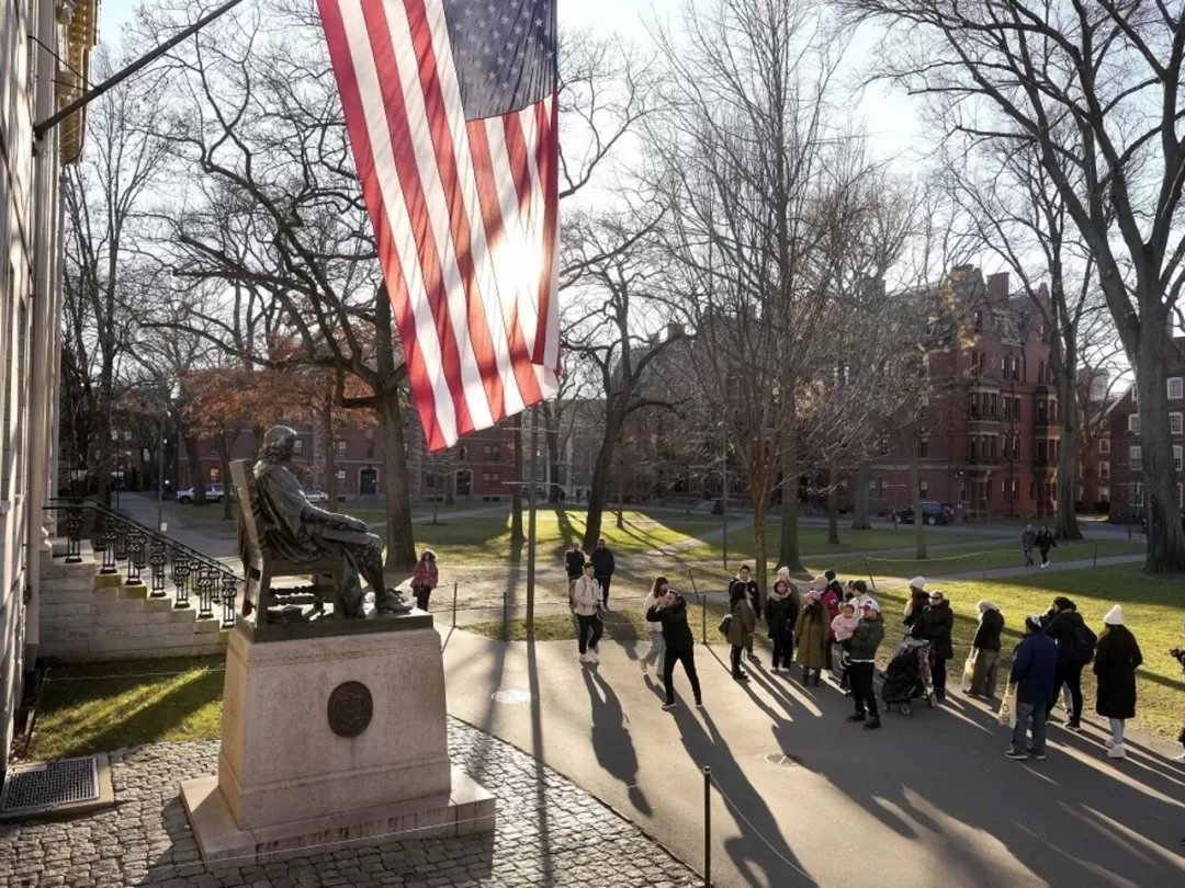 Un groupe de personnes rassemblees dans un parc avec un drapeau americain et une statue en bronze sur un socle en pierre