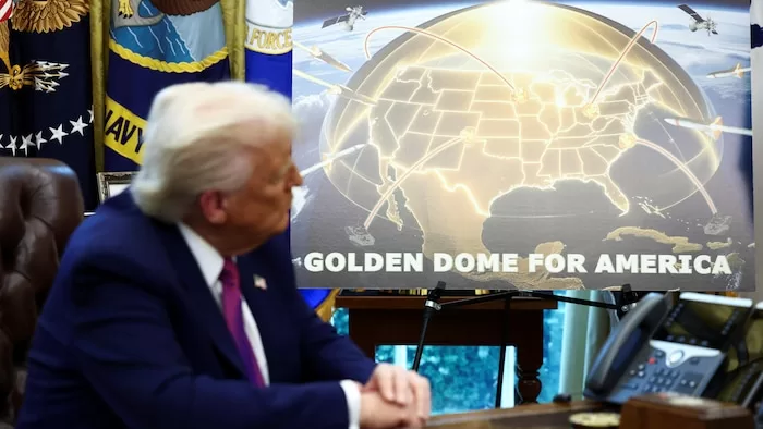 Un homme en costume regarde une grande affiche avec une carte des États-Unis surmontée d'un dôme doré et des lignes de connexion aériennes.