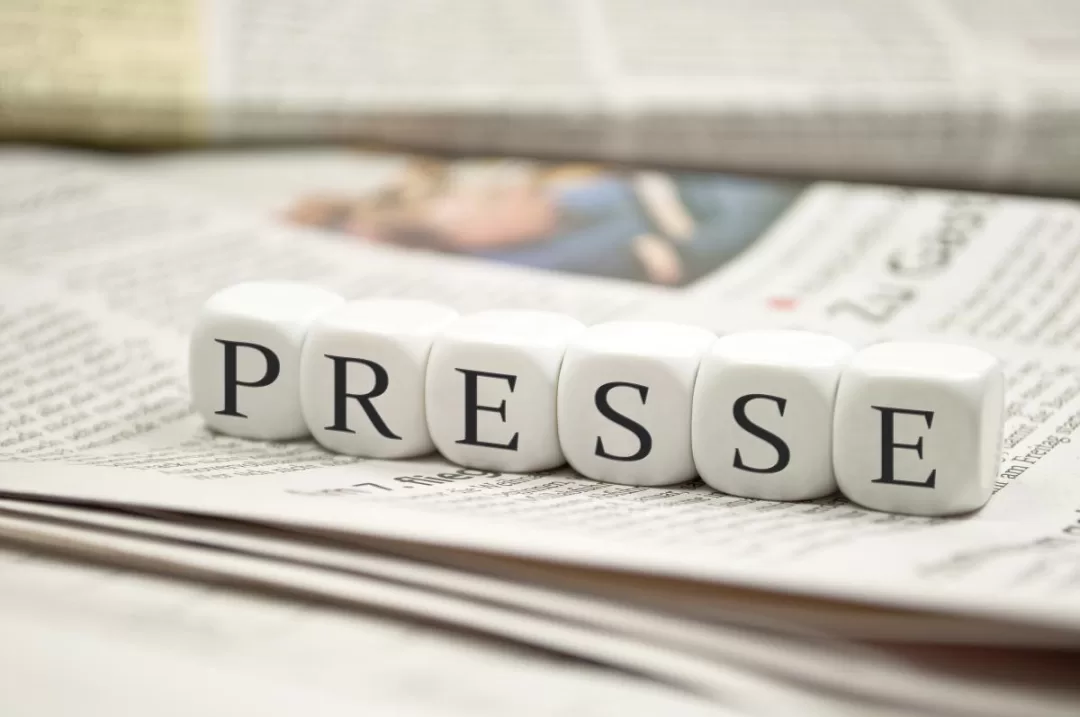 Dés cubes blancs alignés formant le mot PRESSE posés sur un journal ouvert