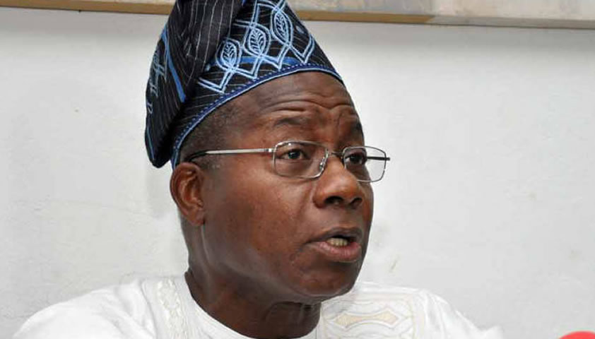 Homme portant un boubou blanc et un bonnet traditionnel bleu parlant en regardant vers la droite