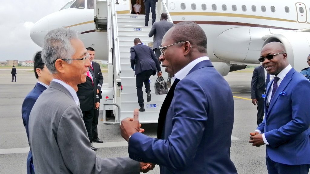 Deux hommes en costume se serrant la main devant un avion privé garé sur le tarmac d’un aéroport