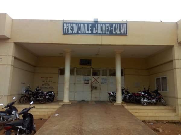 Façade beige d un bâtiment avec un portail fermé et plusieurs motos garées sur les côtés devant l entrée principale