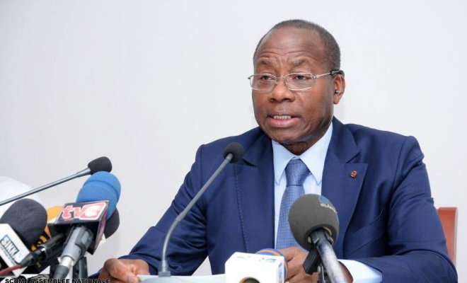 Homme en costume bleu parlant devant plusieurs micros lors d une conférence de presse