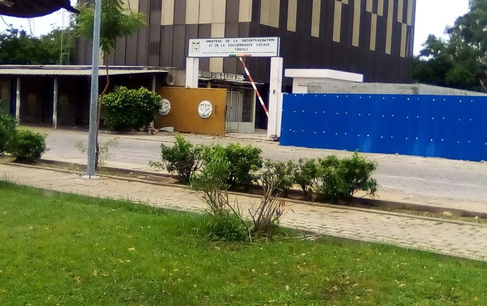 Façade d un bâtiment officiel avec une enseigne portant le nom d un ministère encadré par des jardins et une barrière bleue