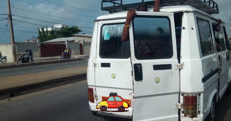 Vue arrière d’une vieille camionnette blanche avec une porte arrière ouverte et un bras sortant par la fenêtre arrière côté passager
