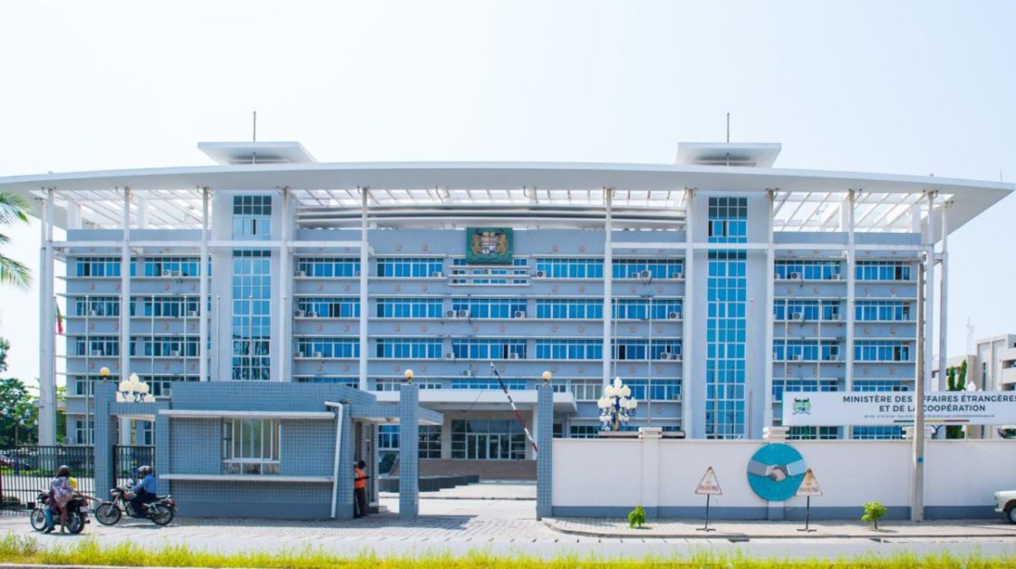 Bâtiment administratif moderne à plusieurs étages avec accès sécurisé et panneaux d'information visibles à l'entrée