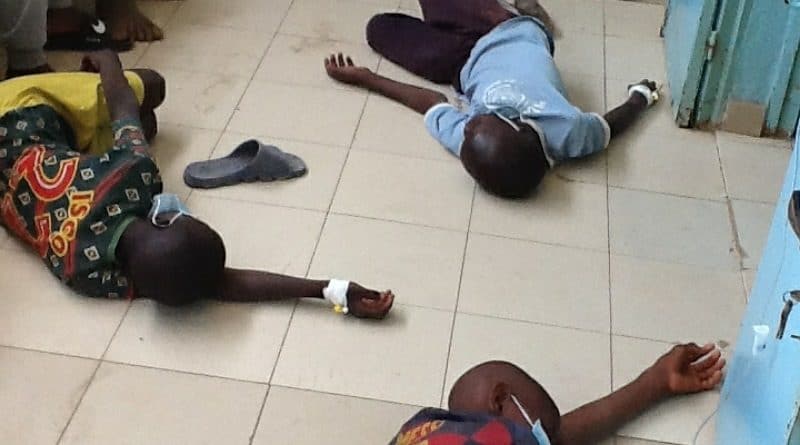 Trois enfants allongés au sol d'une pièce, un des enfants porte un masque chirurgical abaissé sous le visage