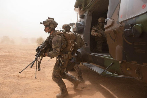 Des soldats en tenue de combat descendent rapidement d un hélicoptère dans un environnement désertique poussiéreux