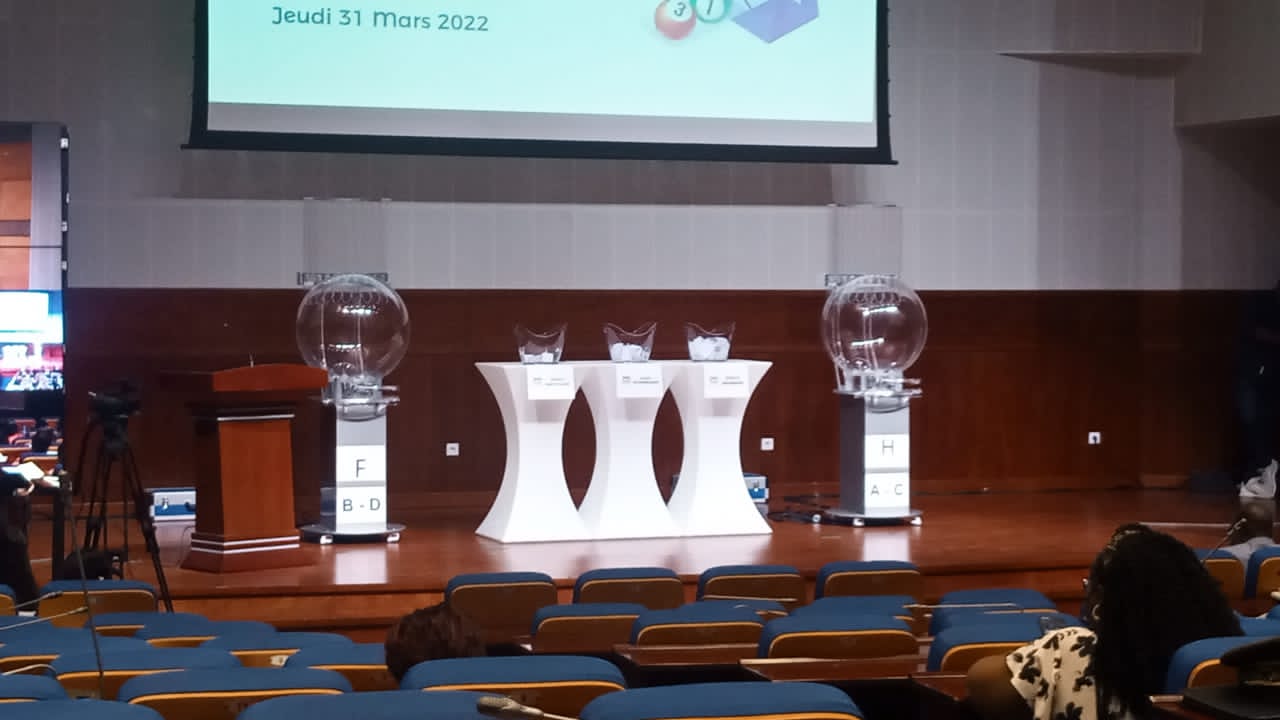Salle avec rangées de sièges vides et présentation avec urnes transparentes et pupitre sur scène