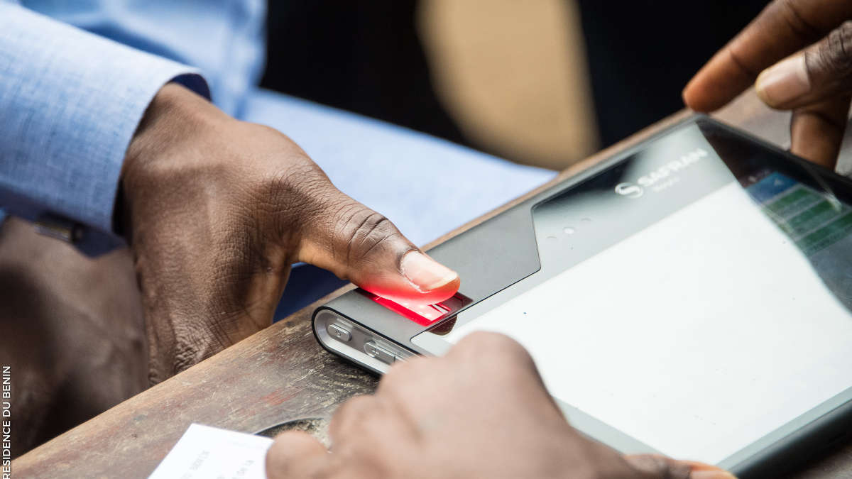 Main appuyant sur un capteur d’empreinte digitale d’un appareil électronique posé sur une table en bois