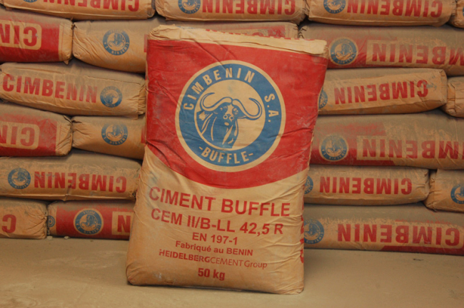 Sacs de ciment empilés avec un sac en avant portant l'inscription CIMENT BUFFLE 50 kg fabriqué au Bénin