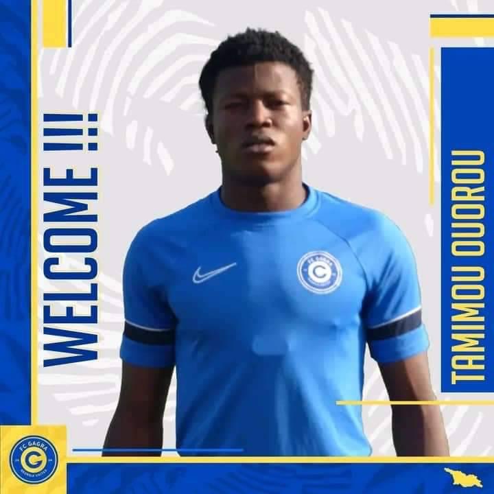 Jeune homme en maillot bleu avec un logo circulaire pose devant un fond blanc et bleu doté du mot welcome