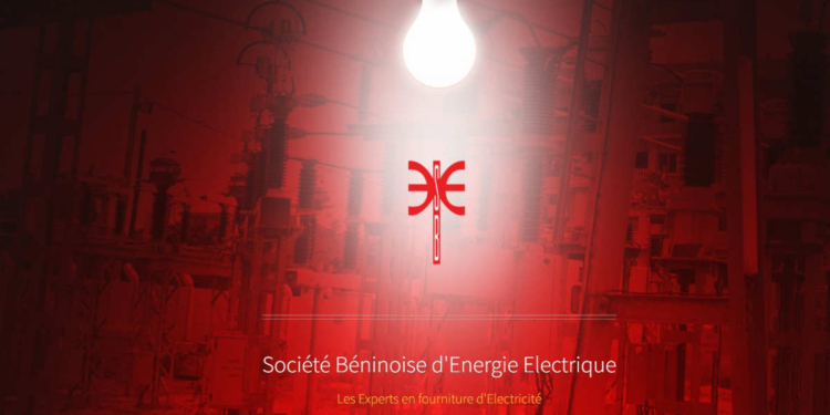 Une ampoule allumée éclaire un panneau avec le logo et le nom de la Société Béninoise d'Énergie Électrique
