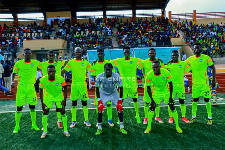 Onze joueurs de football en tenue jaune fluo posant sur un terrain devant des gradins remplis de spectateurs