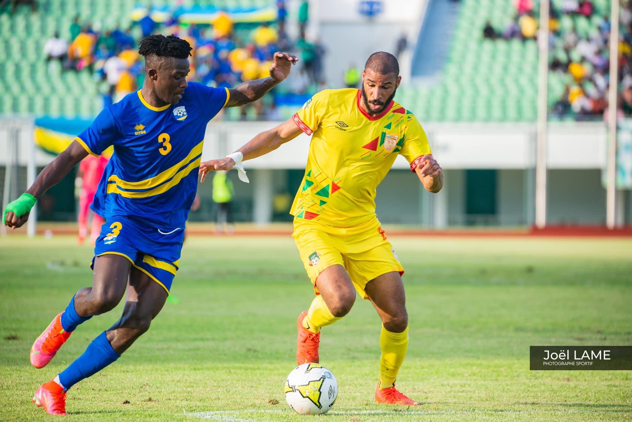 Un joueur en maillot jaune contrôle le ballon sous la pression d'un adversaire en maillot bleu sur un terrain de football