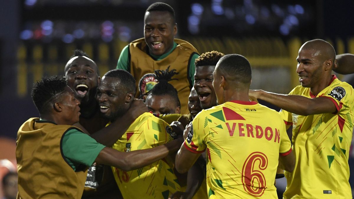 Des joueurs de football en maillots jaunes célèbrent ensemble sur le terrain lors d’un match de nuit