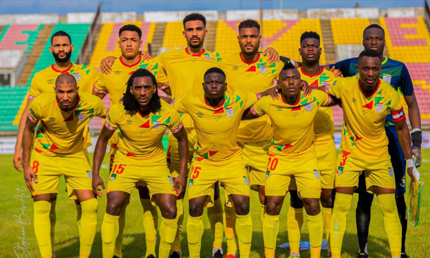 Onze joueurs de football en tenue jaune posent ensemble sur un terrain de jeu devant des gradins colorés