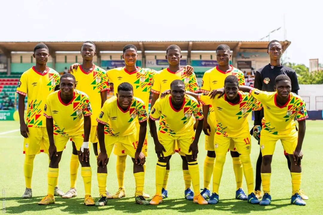 Onze jeunes joueurs de football en tenue jaune posant sur un terrain avant un match sous un ciel clair