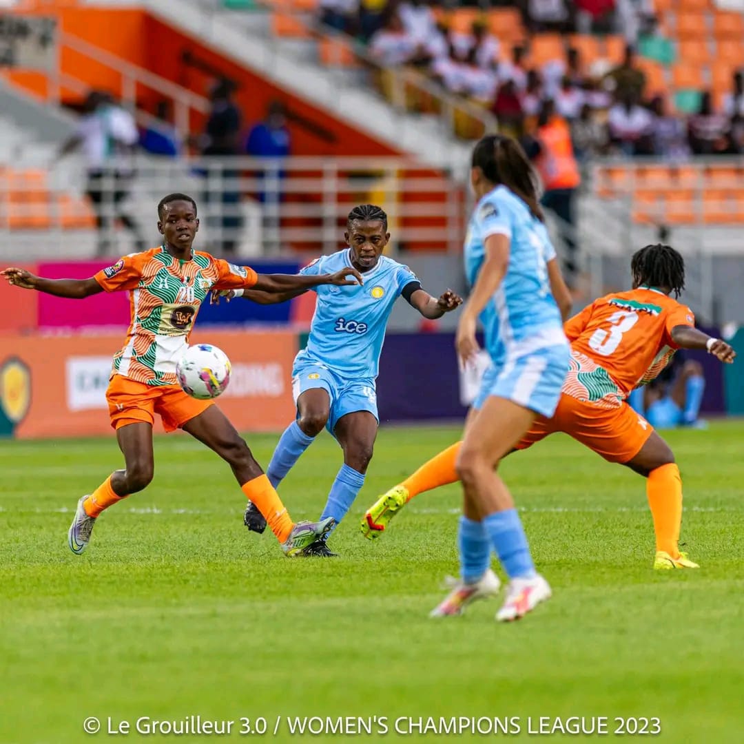 Deux joueuses tentent de s'approprier le ballon lors d'un match de football féminin en tenue orange et bleu clair