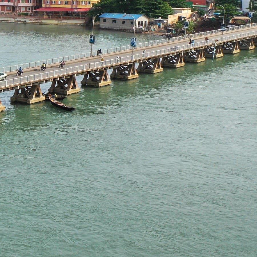 Ancien pont au-dessus d’un cours d’eau avec quelques piétons et motos circulant dessus