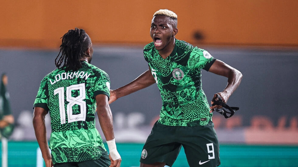 Deux joueurs de football en maillot vert clair sur vert foncé célèbrent un but lors d un match nocturne