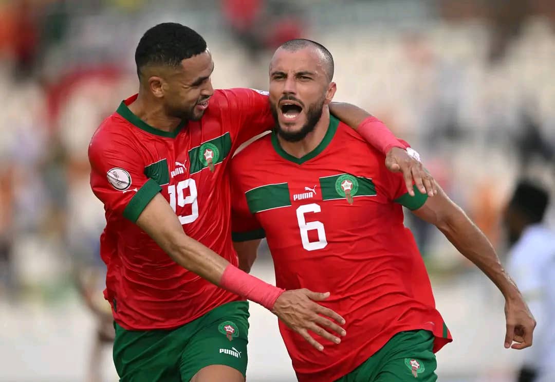 Deux joueurs en maillots rouges célèbrent ensemble un but lors d’un match de football