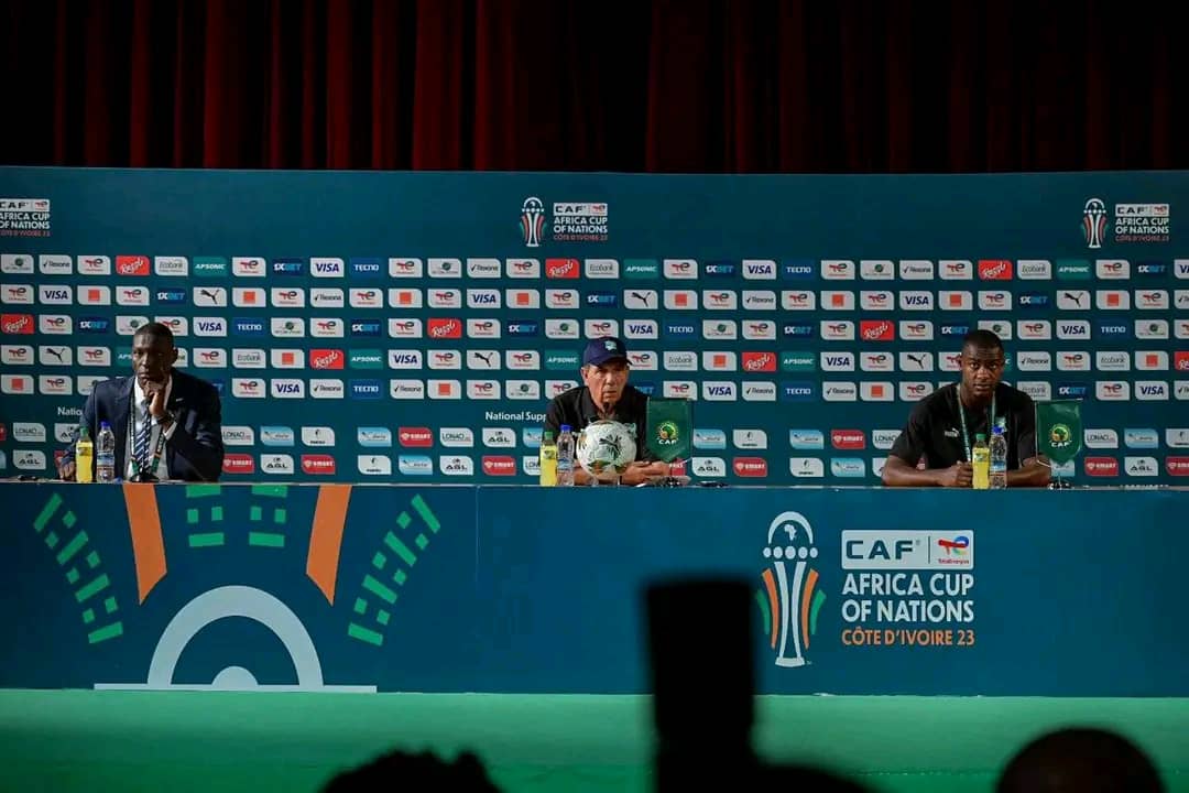 Trois hommes assis à une table lors d une conférence de presse avec le logo CAF Africa Cup of Nations en arrière-plan