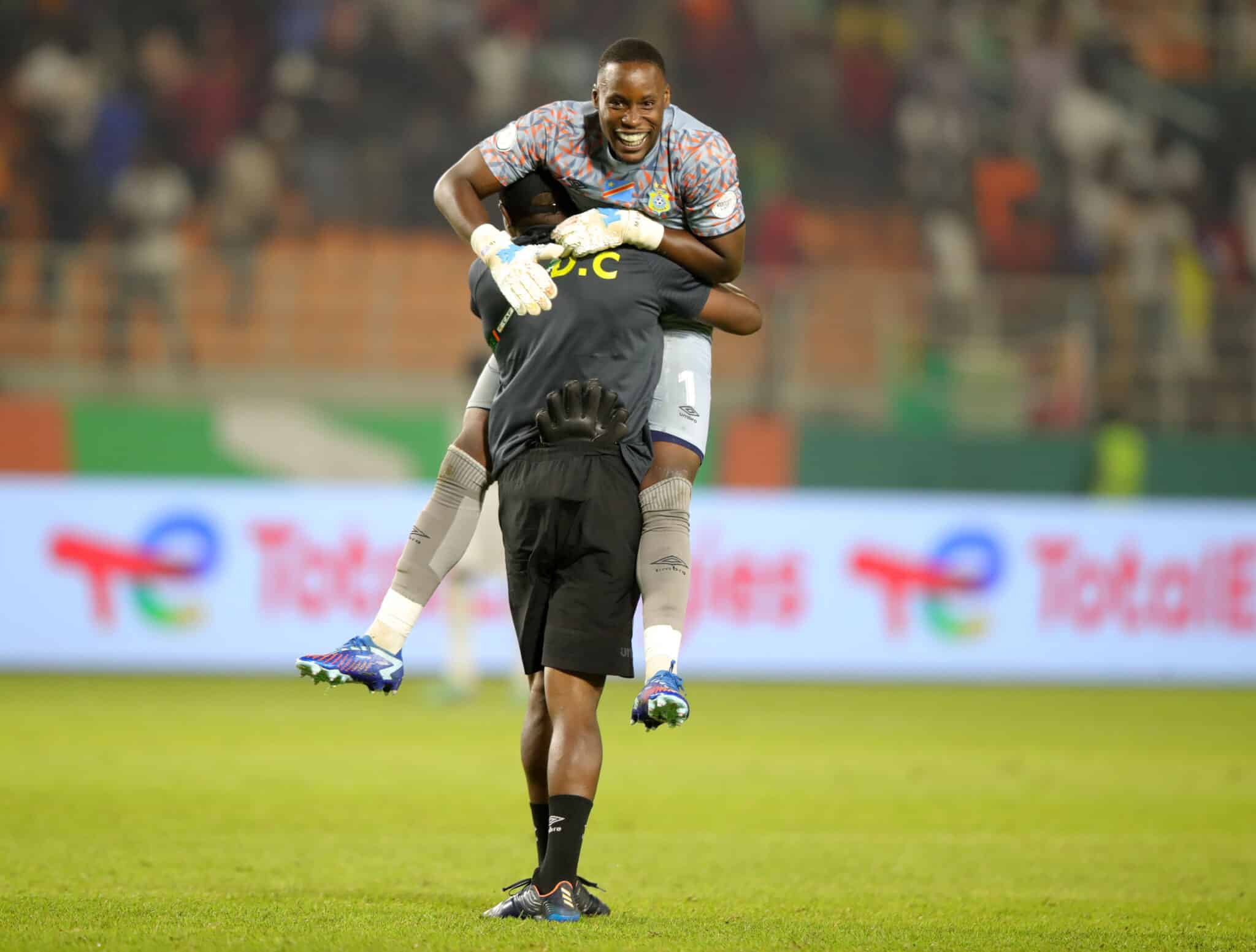 Deux joueurs de football s’embrassant en célébration sur le terrain lors d’un match sous les projecteurs