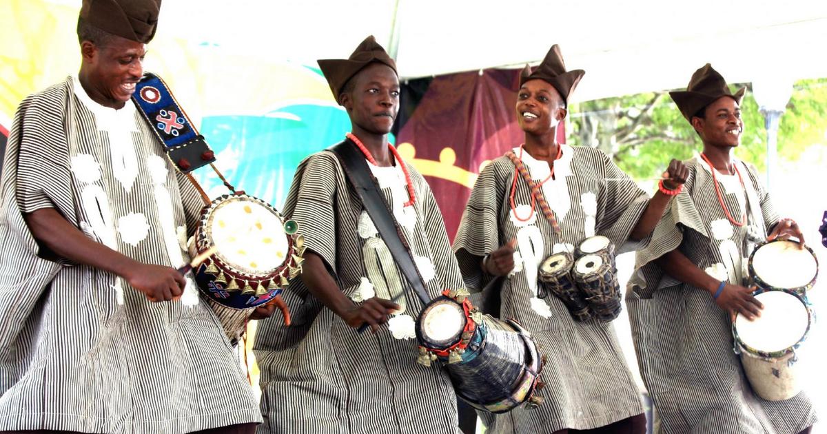 Quatre musiciens vêtus de tenues traditionnelles jouent de divers tambours lors d’une performance en groupe