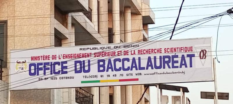 Bannière suspendue entre deux bâtiments indiquant l’office du baccalauréat avec plusieurs fils électriques visibles en premier plan