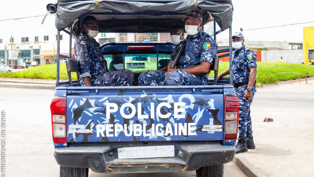 Quatre policiers en uniforme bleu camouflage avec masques dans une pickup de police en ville